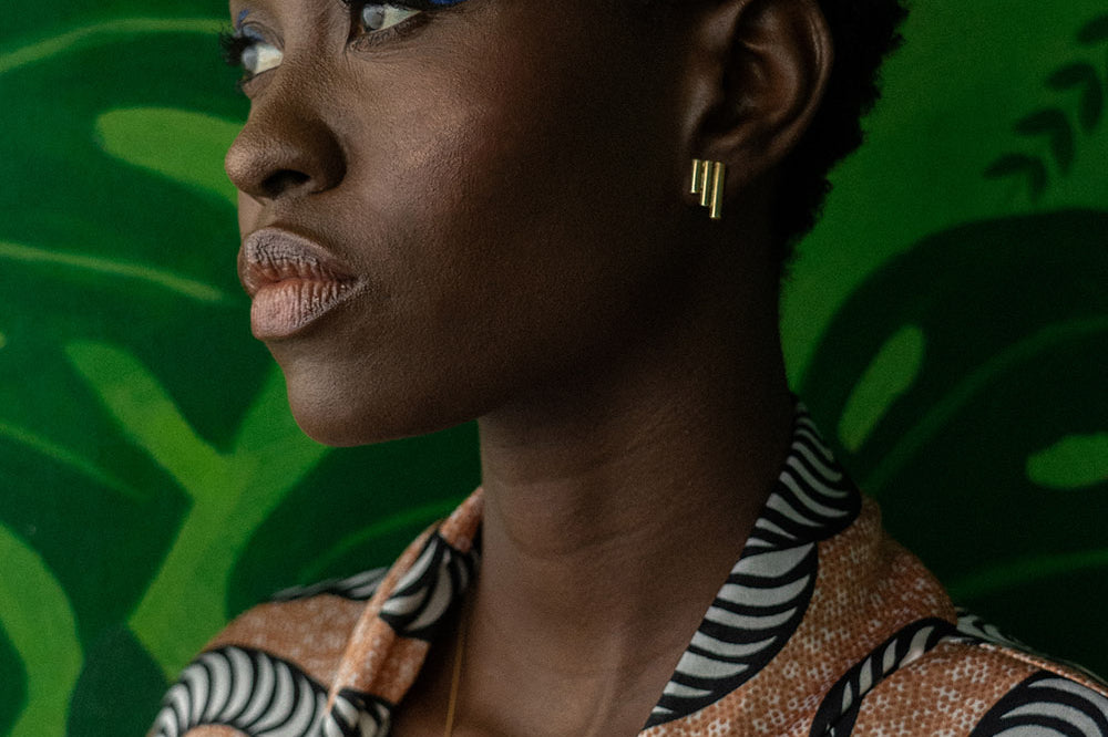 Woman wearing brass Stitched studd earrings by GEOMETRIC. 