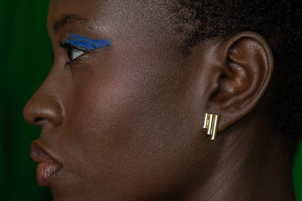 Woman wearing brass Stitched studd earrings by GEOMETRIC.