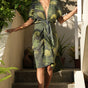 Woman wearing green foilage print wrap dress by Geometric. 
