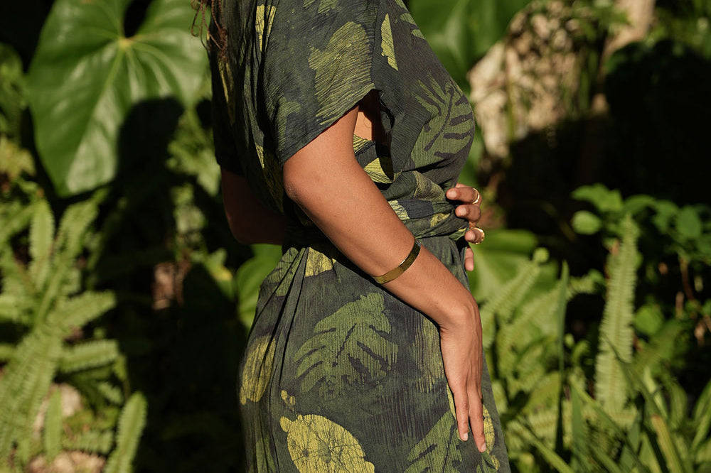 Side View of woman wearing green foilage print wrap dress by Geometric. 