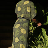 Back view of woman wearing green foilage print wrap dress by Geometric. 
