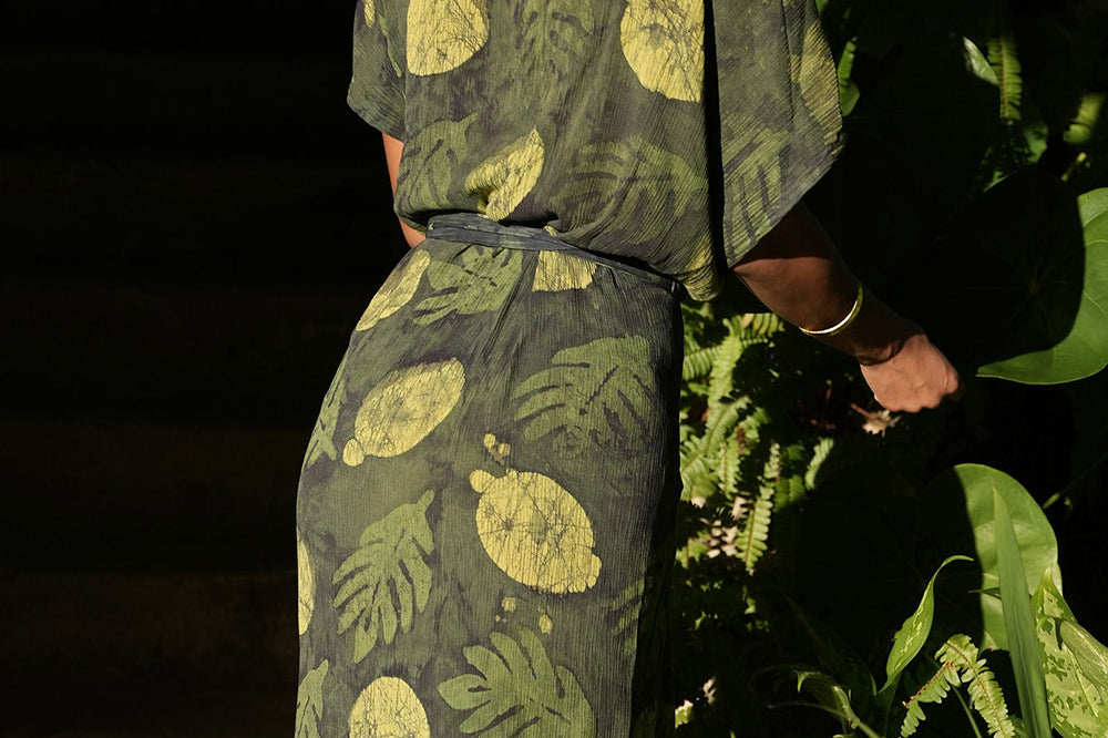 Back view of woman wearing green foilage print wrap dress by Geometric. 