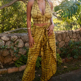 Woman wearing yellow hand-dyed batik print Technno wrap pants by Geometric. 