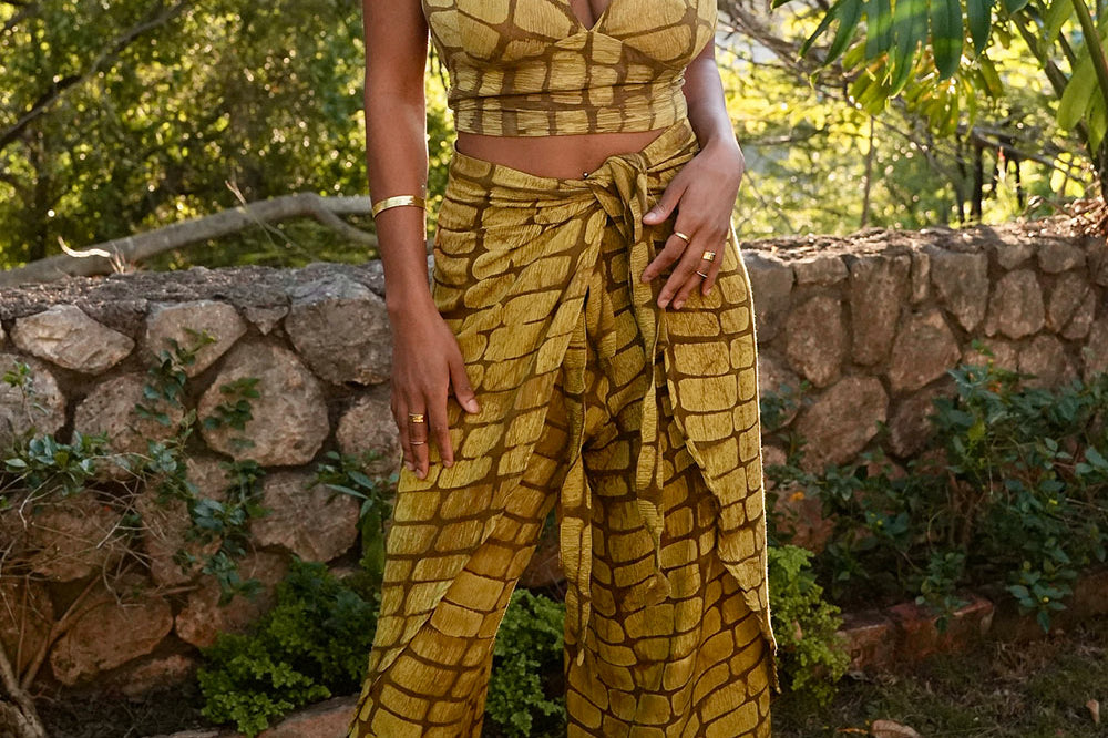 Woman wearing yellow hand-dyed batik print Technno wrap pants by Geometric. 