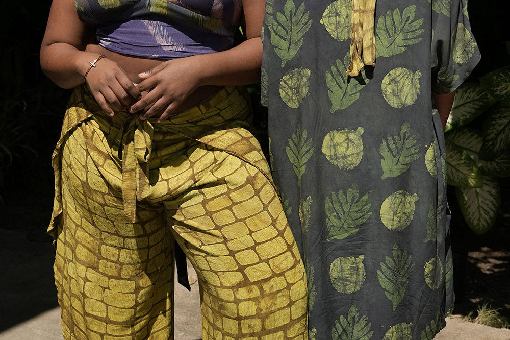 Woman facing camera wearing yellow hand-dyed batik print Technno wrap pants by Geometric. 