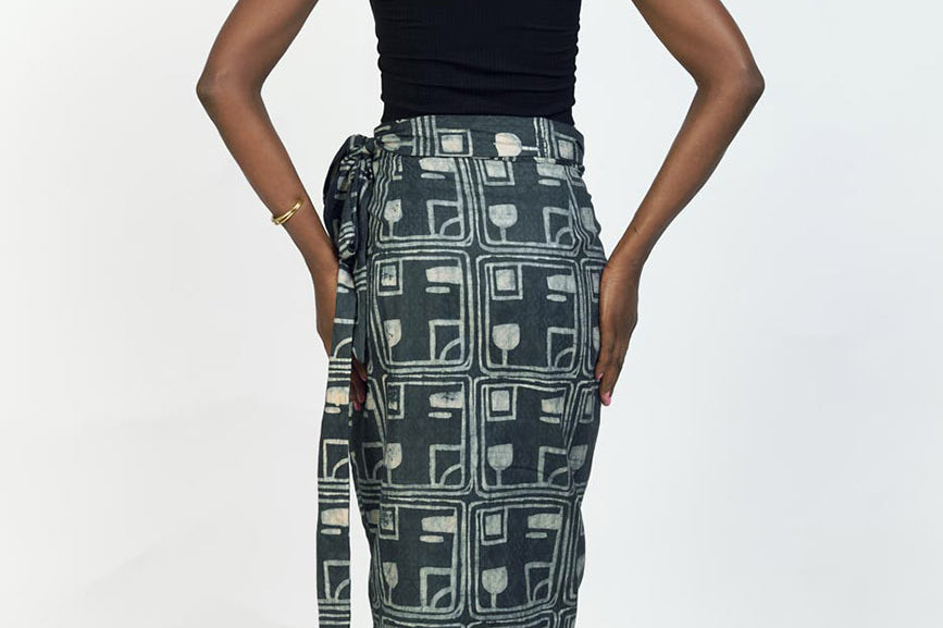 Back view of woman wearing black tank top and charcoal hand-dyed Coco batik print Wrap Skirt by GEOMETRIC. 