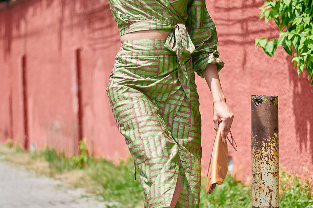 Woman wearing matching green hand-dyed long sleeve wrap top and skirt by GEOMETRIC. 