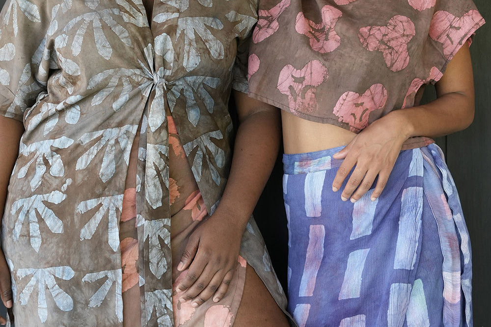 Two women standing together wearing wrap skirt and matching top and kimono jacket by Geometric. Skirt is made from deadstock fabric hand-dyed in purple tone Kaleidoscope print. 