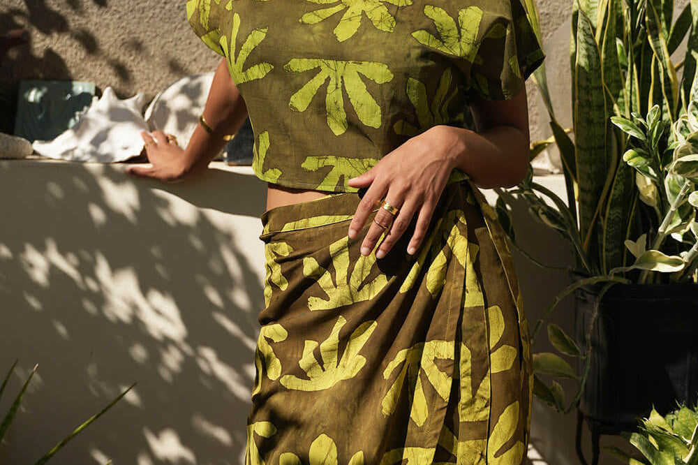 Woman wearing wrap skirt by Geometric. Skirt is made from deadstock fabric hand-dyed in green tone Sunshine print. 