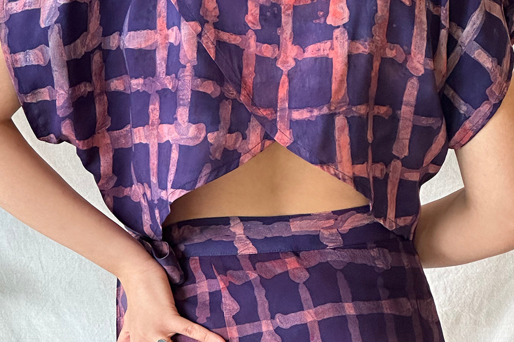 Woman wearing matching purple and pink hand-dyed Caribbean Lattice batik print Reversible Crop Top and Wrap Skirt by GEOMETRIC. 