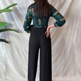 Back view of woman wearing black pants and navy hand-dyed batik Brush Strokes print long sleeve wrap top by GEOMETRIC. 