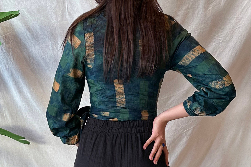 Back view of woman wearing navy hand-dyed batik Brush Strokes print long sleeve wrap top by GEOMETRIC. 