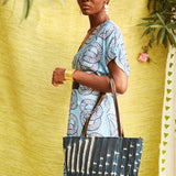 Woman holding Hand-dyed indigo fabric and leather Tema tote bag by GEOMETRIC. 